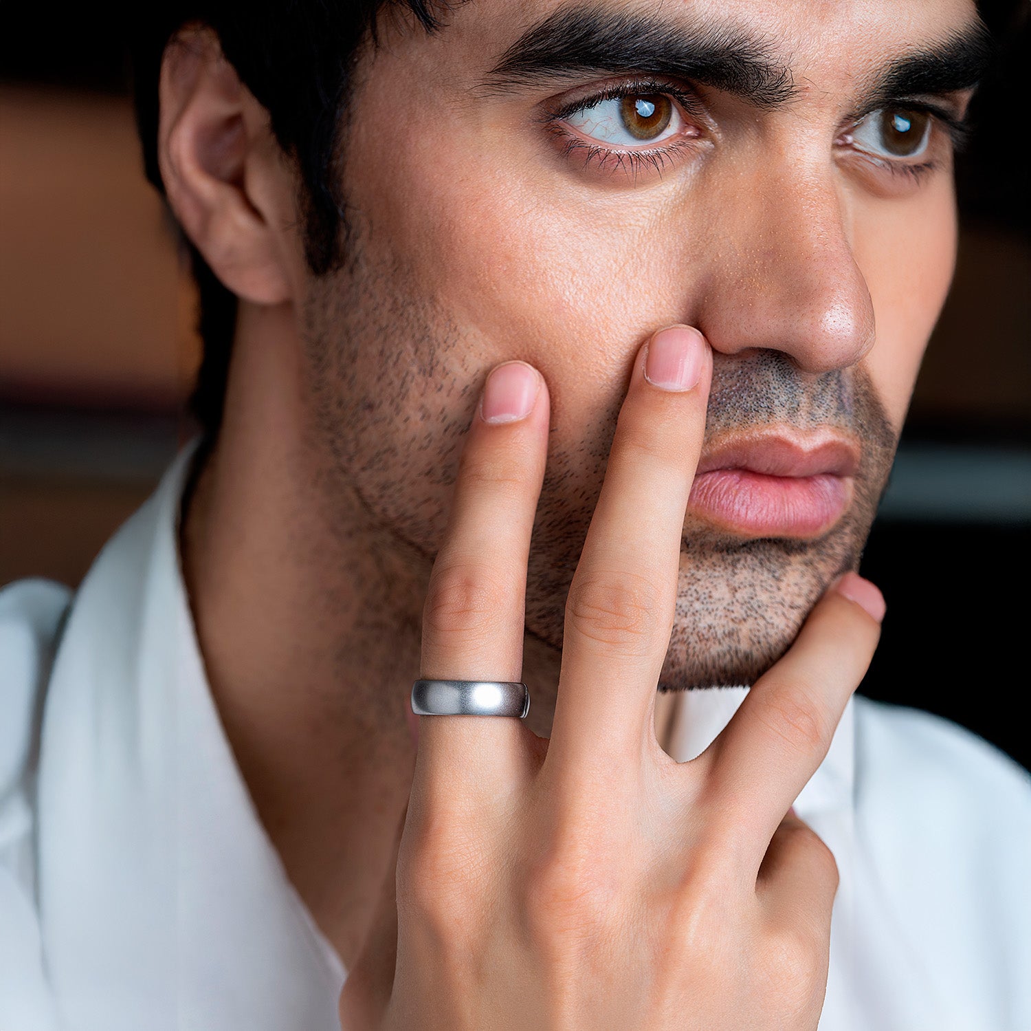 A matte grey metal ring on a light blue background.