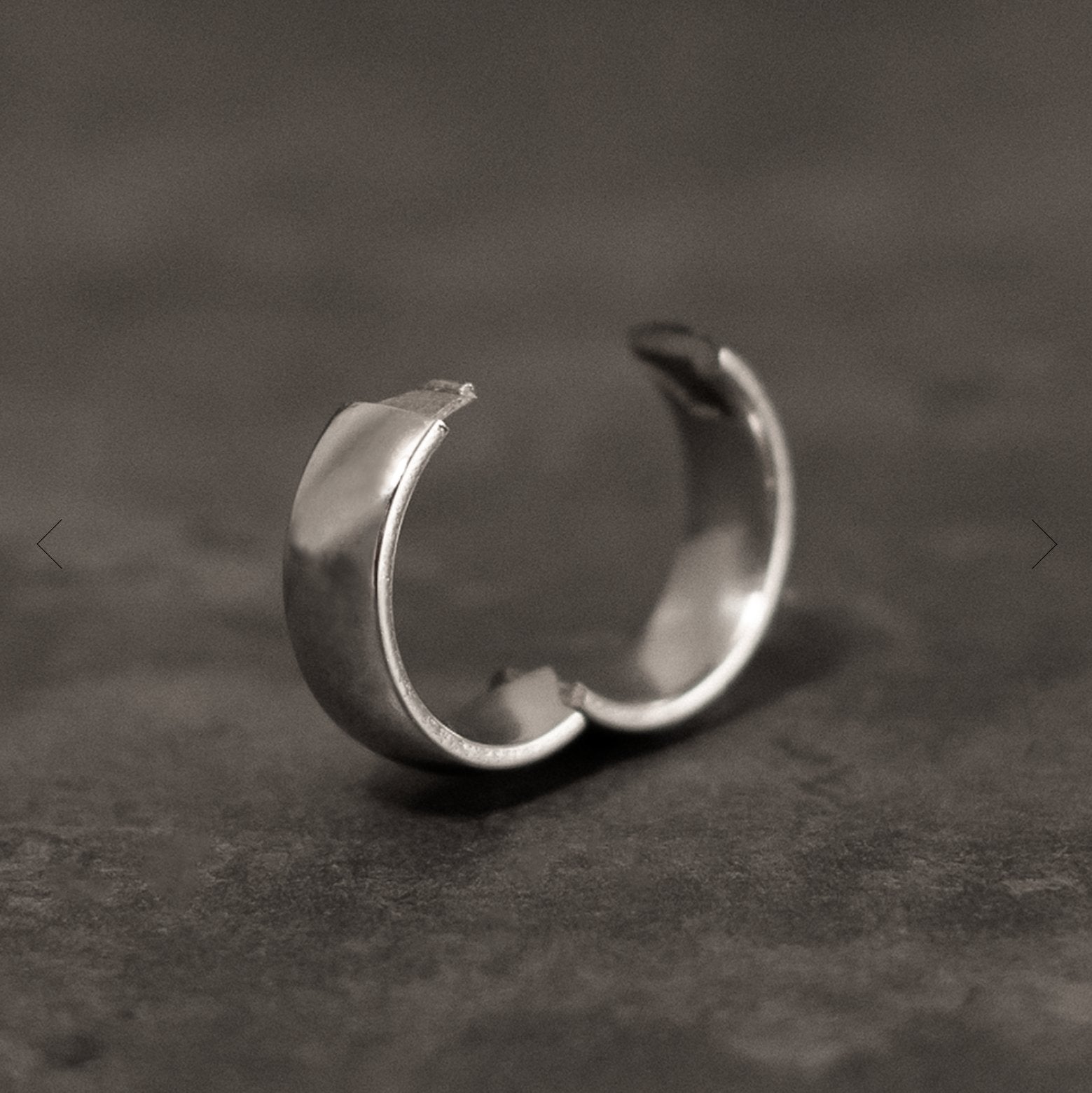 A matte grey metal ring on a light blue background.